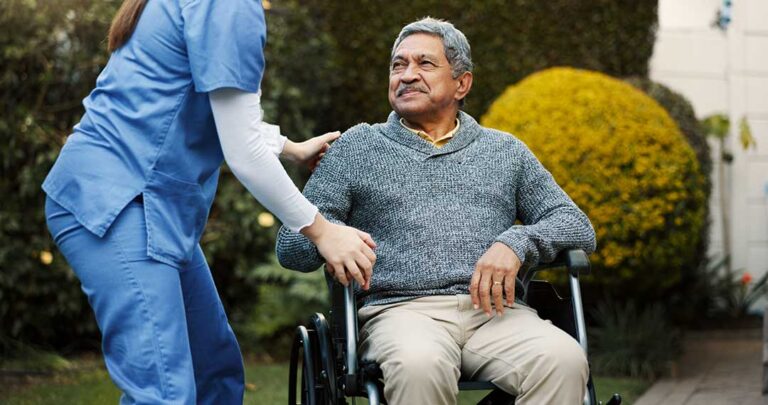 Staff assisting a senior resident during a simulated fire drill in a residential hallway.