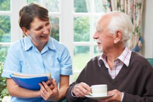 Older adults walk together on a paved path while another resident joins a seated outdoor activity.