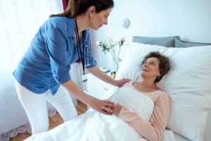 Caregiver reviewing a resident’s medication chart beside an older adult in an assisted living room.